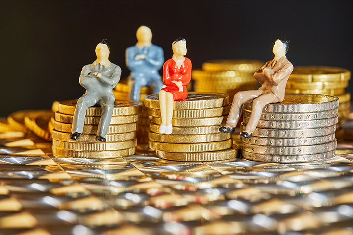 The coins are stacked on top of each other with the figures of business people sitting on them